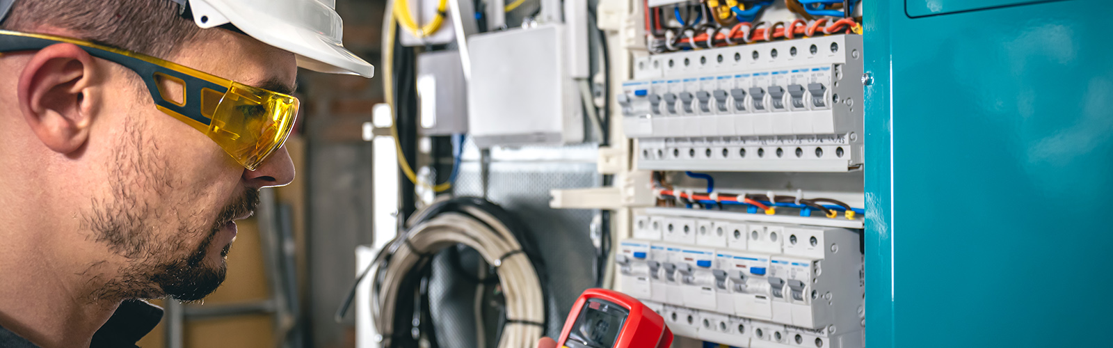 Man, an electrical technician working in a switchboard with fuses.